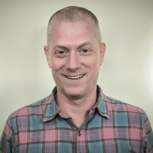 smiling man with short hair wearing a plaid shirt casual style 13th anniversary celebration theme