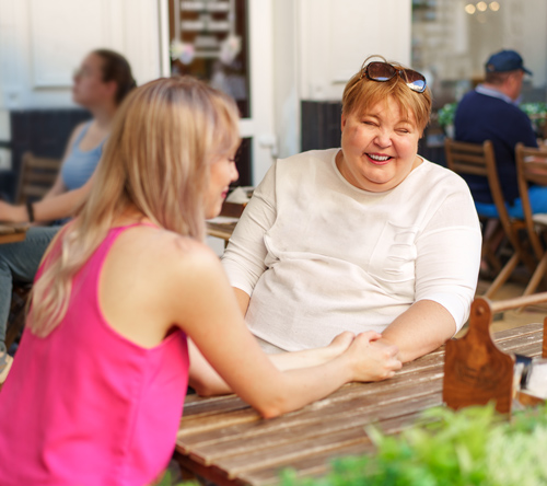 two friends enjoying conversation and laughter in a cozy cafe setting with natural light