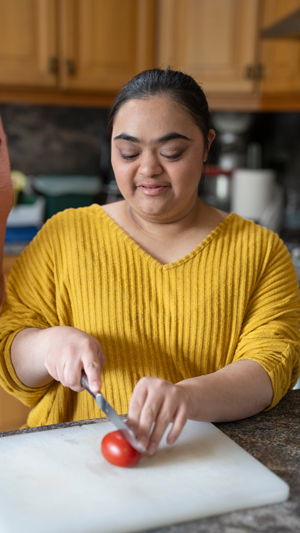 woman in yellow sweater slicing a tomato in kitchen preparing healthy meals six ways to enjoy tomatoes