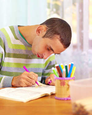 young man coloring in a book with colorful markers highlighting educational activities 9 year old creativity