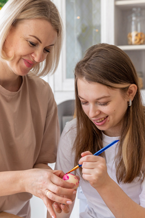 a woman and girl painting decorative eggs in a kitchen joyful activity for spring decorating eggs together creative bonding experience eight colorful designs