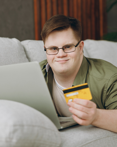 person using a laptop holding a credit card sitting on a couch online shopping experience