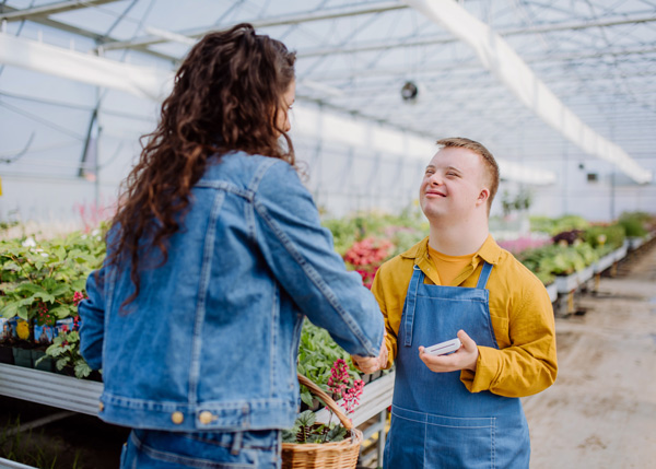 person shaking hands in greenhouse with flowers colorful plants gardening techniques