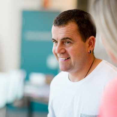 smiling man wearing a white shirt in a casual setting discussing three important topics with another person