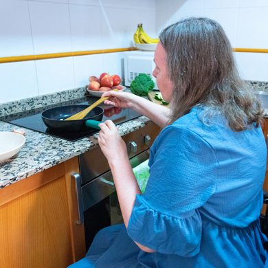 woman cooking in kitchen with frying pan and vegetables healthy meal preparation